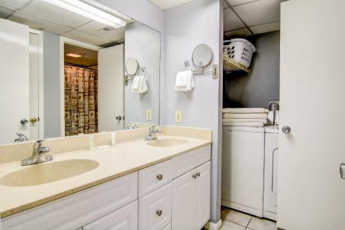 a bathroom with two sinks and a washer and dryer at Sand & Surf Sea Mist Condos in Port Aransas