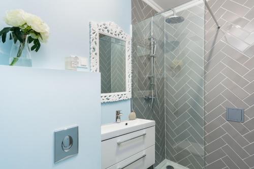 a bathroom with a sink and a shower with a mirror at Elite Apartments Piwna Premium in Gdańsk