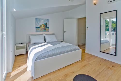 a white bedroom with a bed and a mirror at Apartments Bubalo in Hvar