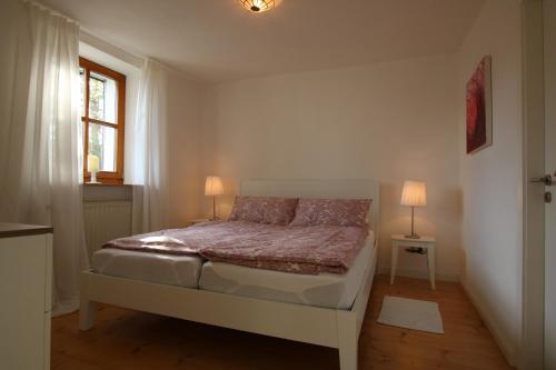 1 dormitorio con 1 cama con 2 lámparas y una ventana en Schicke Ferienwohnung für 2, en Niederkalbach