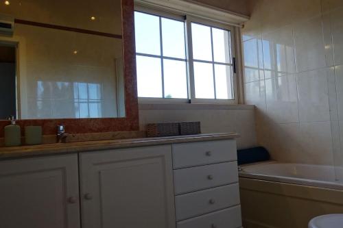 une salle de bain avec un lavabo, une baignoire et un miroir dans l'établissement Margarida Charming House in Cascais, à Cascais