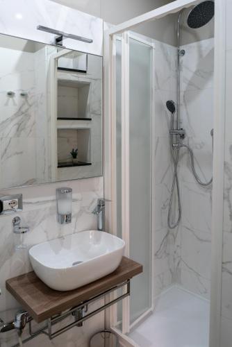 a white bathroom with a sink and a shower at Marranzanu Rooms in Santa Teresa di Riva