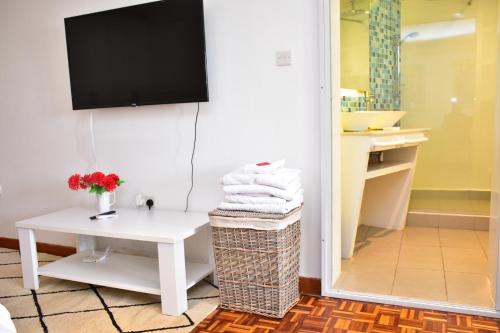 a bathroom with a white table and a tv on the wall at Maison Mitwaba in Nairobi