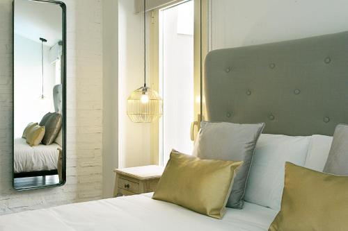 a bedroom with a white bed with a large mirror at Graffiti Suites Málaga in Málaga