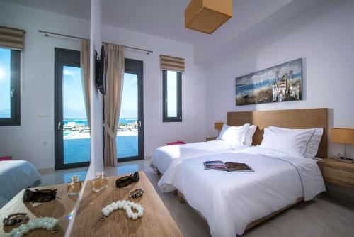 a bedroom with two beds and a table and windows at Villa Bellelen in Agios Nikolaos
