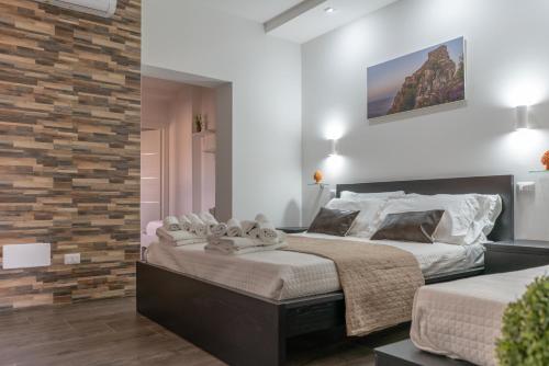 a bedroom with a large bed and a brick wall at Marranzanu Rooms in Santa Teresa di Riva