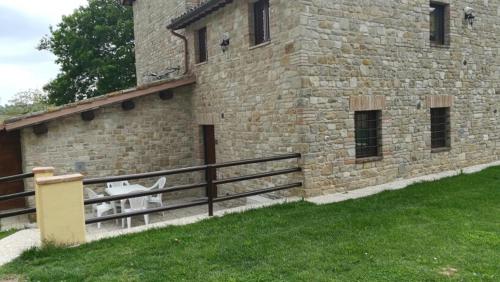 a brick building with a fence next to a grass field at BorgoPratole CountryHouse in Cingoli