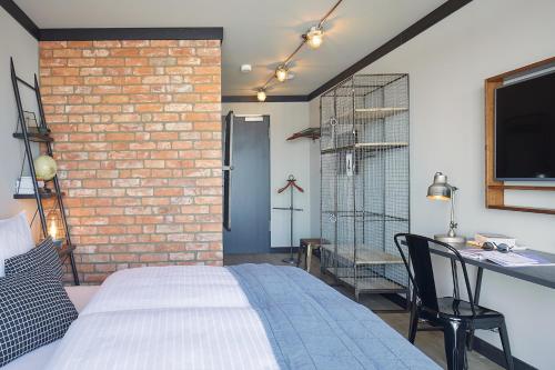 a bedroom with a brick wall and a bed and a desk at Fliegerdeich Hotel & Restaurant in Wilhelmshaven