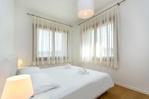 a white bedroom with a large white bed with windows at Premium Apartment Maj **** in Poreč