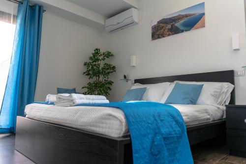 a bedroom with a bed with a blue blanket on it at Marranzanu Rooms in Santa Teresa di Riva