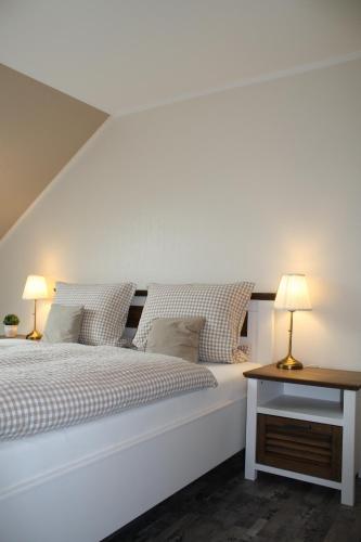 a bedroom with a white bed with two lamps at Alte - Post - Hotel in Schöppingen