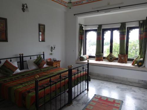 a bedroom with a bed in a room with windows at Karohi Haveli - A Heritage Hotel in Udaipur