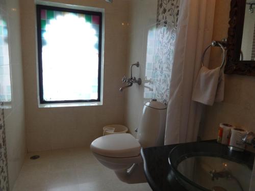 a bathroom with a toilet and a sink and a window at Karohi Haveli - A Heritage Hotel in Udaipur