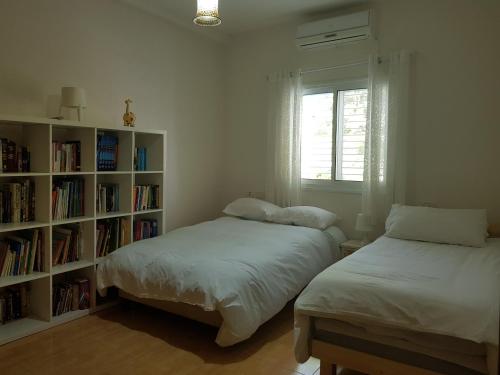 um quarto com duas camas e uma estante de livros em Bertha's Coffee em Afula