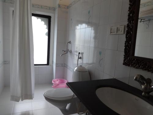a bathroom with a sink and a toilet and a mirror at Karohi Haveli - A Heritage Hotel in Udaipur