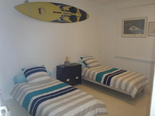 Deux lits dans une chambre avec une planche de surf sur le mur dans l'établissement SEA and BOAT, à Le Portel