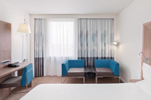 a room with two chairs and a table in a hotel room at Novotel London Excel in London