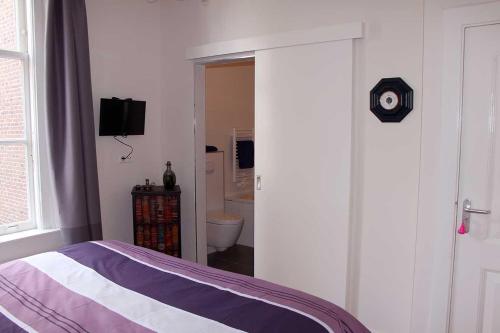 a bedroom with a bed and a door to a bathroom at B&B Utrecht Domkwartier in Utrecht