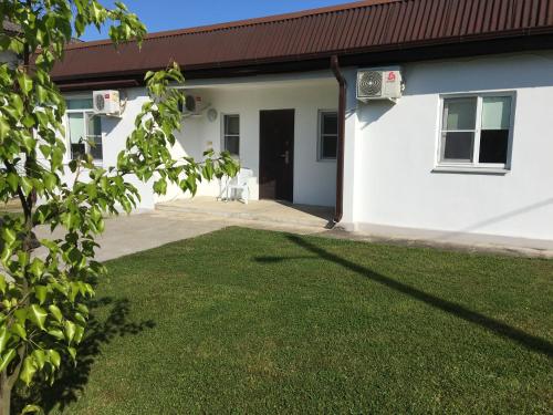 a white house with a lawn in front of it at Guest house Amza in Ochamchira