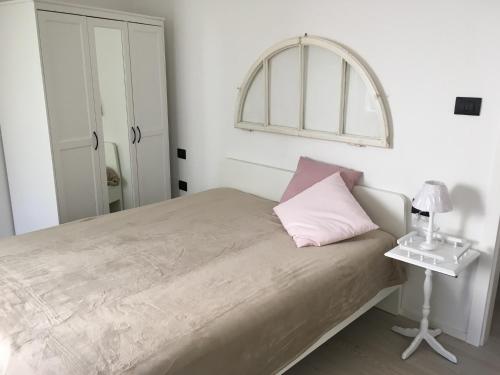 a white bedroom with a bed and a table at Appartamenti Ora del Garda in Nago-Torbole