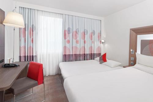 a hotel room with two beds and a desk at Novotel London Excel in London