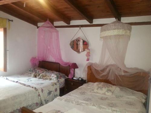 two beds in a room with pink curtains at Oikos Jullia in Promírion