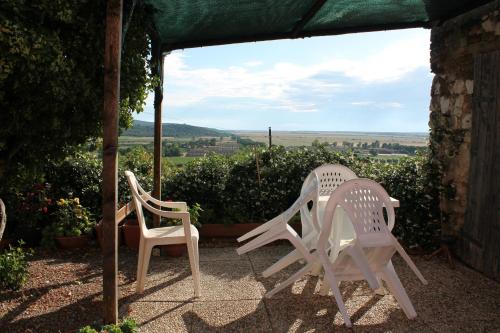 two white chairs sitting on a patio with a view at Agriturismo Podere Montenero in Alberese