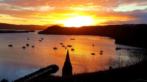 a sunset over a body of water with boats at Kirk Cottage in Tobermory