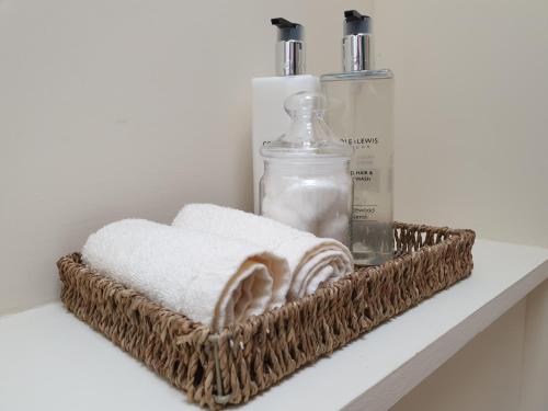 - un panier avec des serviettes et une bouteille de savon sur une étagère dans l'établissement Kirk Cottage, à Tobermory