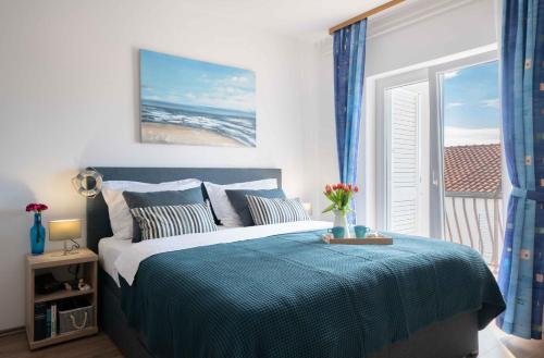 1 dormitorio con 1 cama con manta azul y ventana en Apartments Valentino, en Vodice