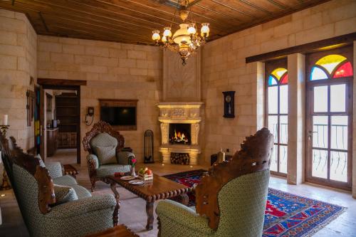 a living room with a fireplace and chairs and a chandelier at Kayakapi Premium Caves Cappadocia in Ürgüp
