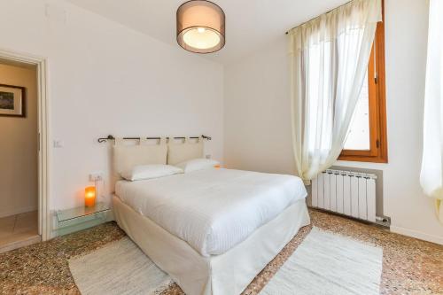 Habitación blanca con cama y ventana en Fortuny Loft, en Venecia