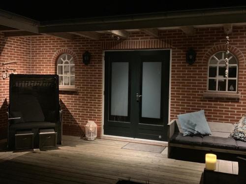 a brick building with a black door and a couch at De Strandkorf in Roodeschool