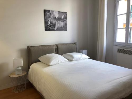 une chambre avec un lit avec des draps blancs et une fenêtre dans l'établissement Vieux port de Cannes, à Cannes