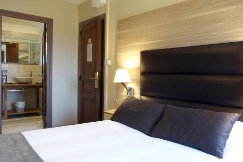 a bedroom with a bed with a black headboard and a bathroom at LOGIS HOTEL - Auberge de l'Hélix in Rosoy