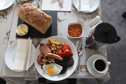 a table with a plate of breakfast food and a cup of coffee at Craigmount in Wigtown