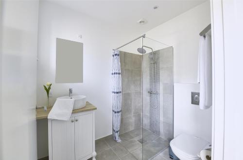 a white bathroom with a sink and a shower at Hotel Skovpavillonen in Kerteminde