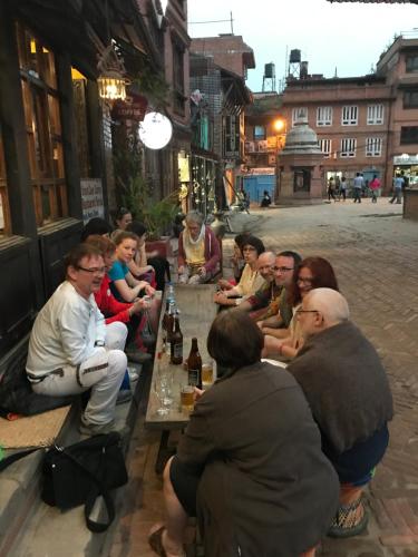 a group of people sitting around a table on a street at Shiva Guest House in Bhaktapur