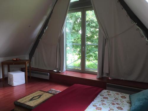 une chambre avec un lit et une grande fenêtre dans l'établissement Gite La Bouverie, à Saint-Aubin-le-Cauf