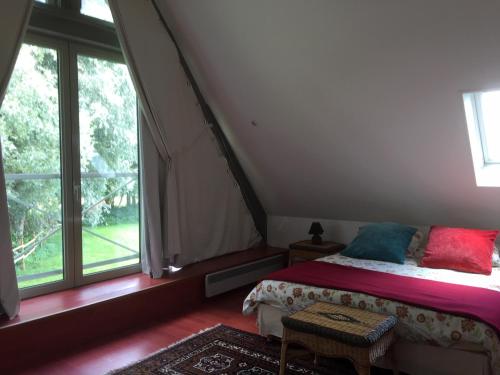une chambre avec un lit et une grande fenêtre dans l'établissement Gite La Bouverie, à Saint-Aubin-le-Cauf