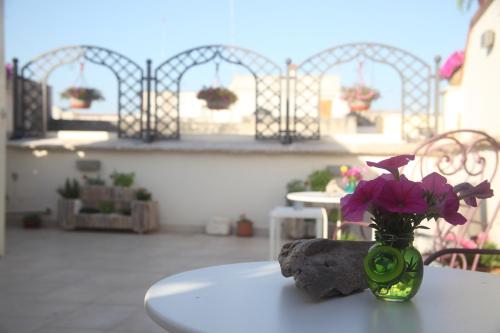 un vaso con fiori viola seduto su un tavolo di 3 Archi B&B a Trani