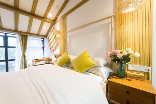a bedroom with a white bed and a vase of flowers at Tongli Slowlife River View Inn in Suzhou