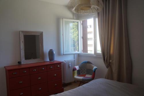a bedroom with a dresser and a mirror and a chair at 80m tres lumineux parking priv in Nîmes