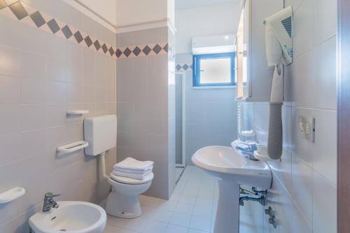 a white bathroom with a toilet and a sink at Residence Baltic in Cattolica