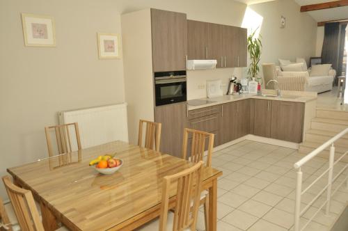 uma cozinha com uma mesa de madeira com uma taça de fruta em Holiday Home 't Regulierenhuisje em Tongeren
