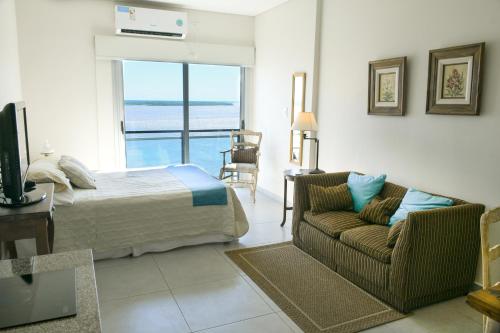 een slaapkamer met een bed, een bank en een raam bij Torre Costanera Norte in Corrientes