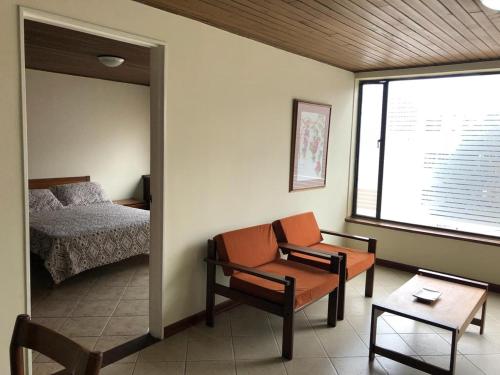1 dormitorio con cama, silla y espejo en Apartamentos Percales, en Bogotá