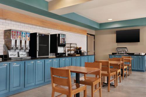 Country Inn & Suites by Radisson, Bowling Green, KY في بولينغ غرين: مطعم فيه دواليب زرقاء وطاولة وكراسي