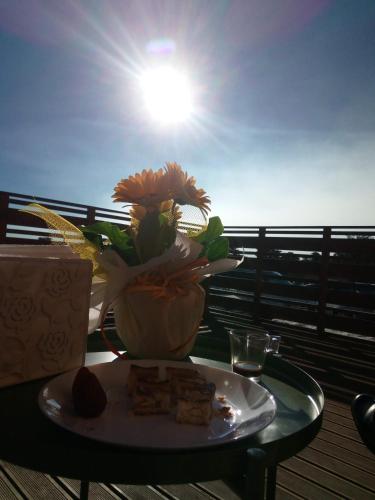a plate of food on a table with a vase of flowers at Rifugio Il Ginepro dell'Etna in Linguaglossa