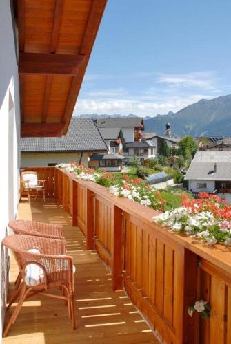 a wooden balcony with chairs and flowers on it at Apart Hotel Garni Kofler in Fiss